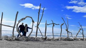 Standing in the iconic driftwood beach sign of Hokitika, west coast of the South Island, New Zealand